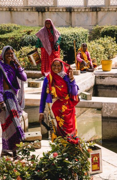 Solo female travel in India 
4 Indian women in sari, vibrant colours, purples, red, orange, in garden