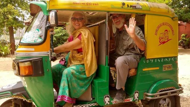 Solo female travel in India 
Woman and man in green and yellow tuk tuk, woman wearing green and yellow traditional dress seated in front, man in beige trousers and beige checked shirt sat in back