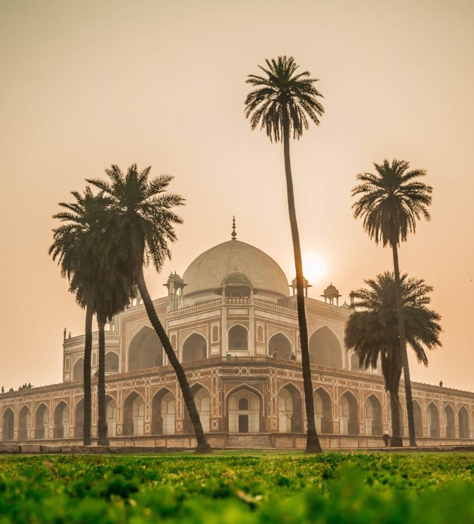 Indian Temple, cream with ornate tile work  with smog causing a haze orange tints , palm trees in front