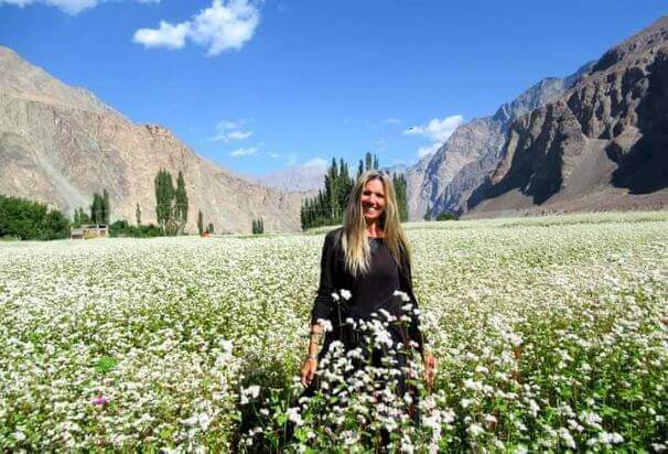 Solo female travel in India 
Veronica in Turtuk, India, close to the Pakistan border, standing in field of white flowers wearing black dress, mountains in background