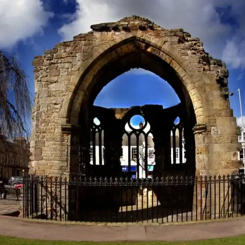 Stone archway ruin with gothic black iron arched windows to rear and black iron fence in front