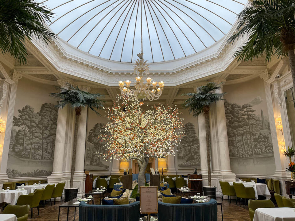 Edwardian looking lounge, The Palm Court within the Balmoral Hotel, Edinburgh, large glass dome dominates, cream columns around edge and palm trees