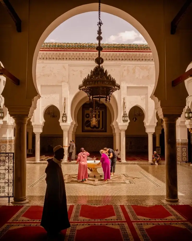 Second city Fez. Morocco A tiled building with an open square with a drinking fountain.  People in local dress