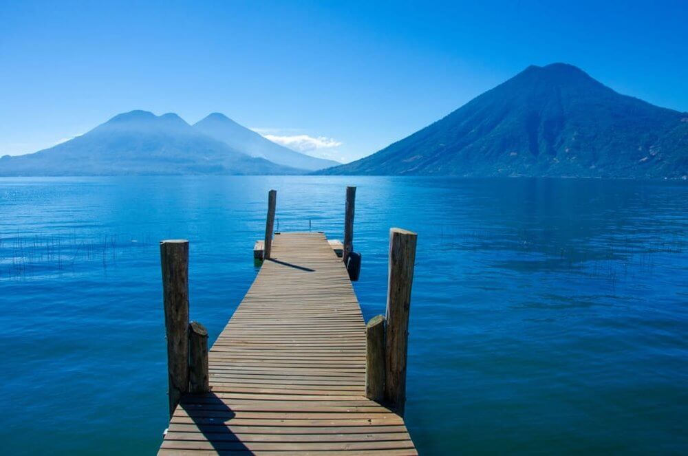 Deep blie lake, mountains at far side blue sky , wooden jetty