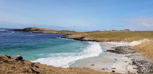 Shetland Highlights beaches
Looking over bay with white sand beach and turquoise sea, deepening to deep blue further out from shore brown fields on all sides