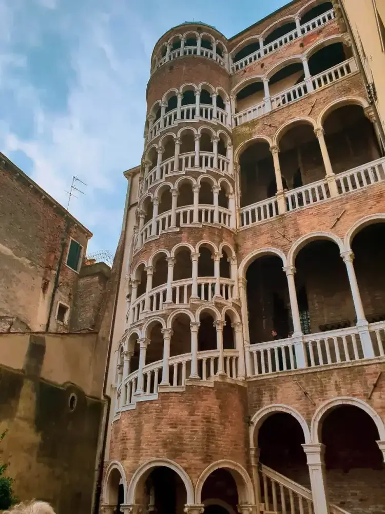 Being a tourist in Venice
spiral staircase with baulustrades and columns in cream stone, the rest in pinkish bricks arches, arches along corridors and up stairs 