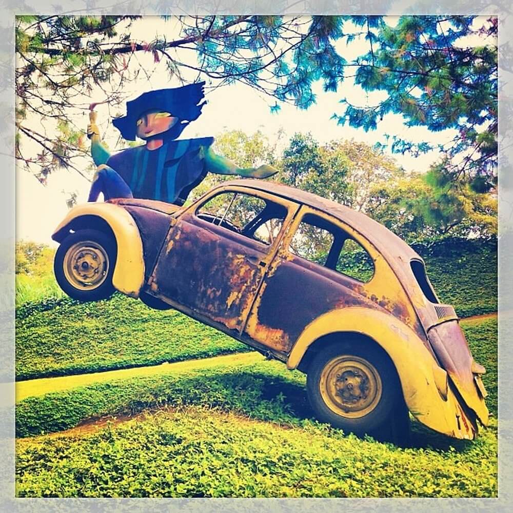 Second city Antigua, Guatemala. Rusted VW yellow beetle with sculpture of woman sat on bonnet