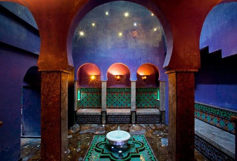 Second city Fez, Morocco.  Inside a hamman, turquoise tiles, arches, purple walls, seating around the edges and a fountain in the centre