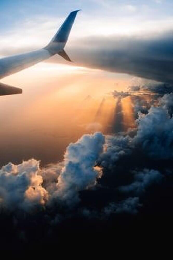  Wing of airplane against orange sunset and clouds