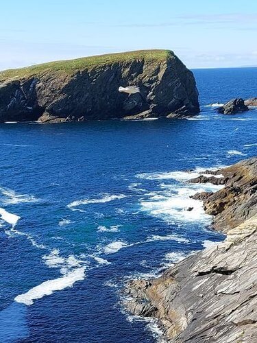 Cliffs with green topped fields deep blue sea and blue sky