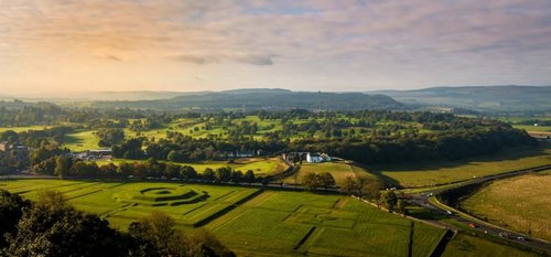 Looking down into Kings Knot Gardens all green, green fields and trees in background, pink sky on white clouds