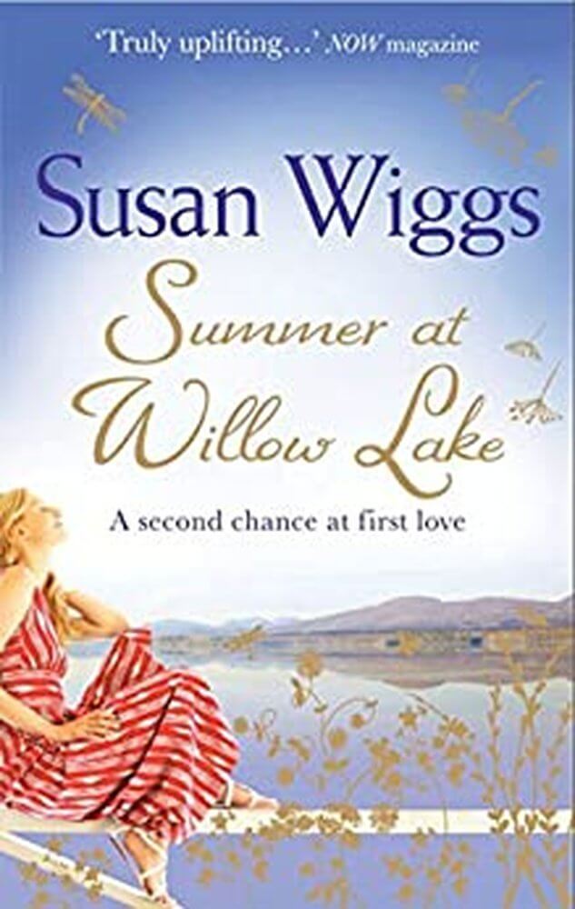 Cover of Summer at Willow Lake by Susan Wiggs tagline A second chance at first love. title in gold cursive, other in deep purple.  Image of woman sat on fence looking over lake and sky in blue.woman is wearing a red striped sundress and white sandles