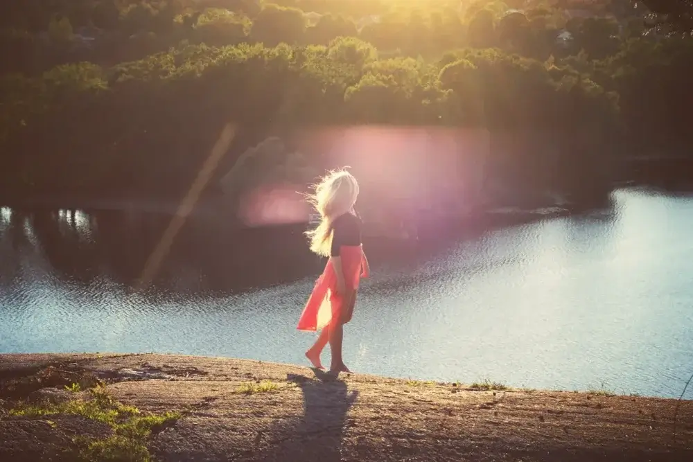 solo travel fears end photo woman walking barefoot above lake surrounded by trees