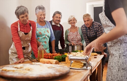 Group of older adults at a cooking class standing around a table with ingredients